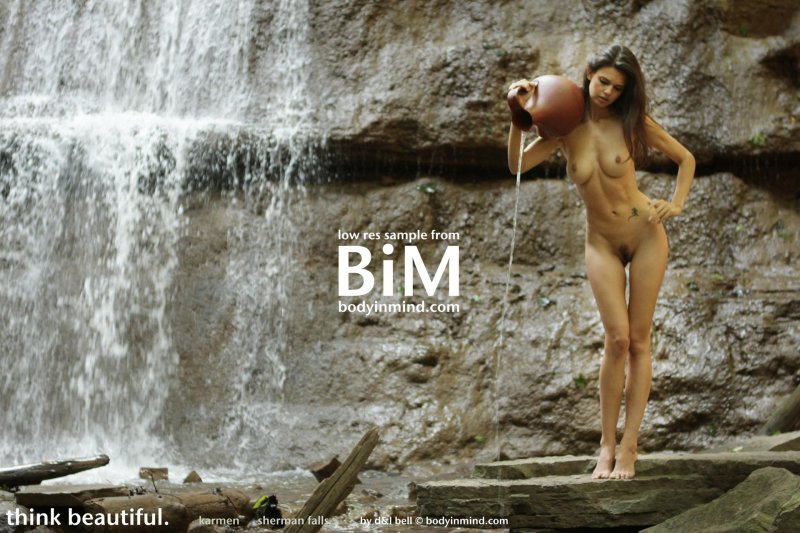 Nude girl under a waterfall